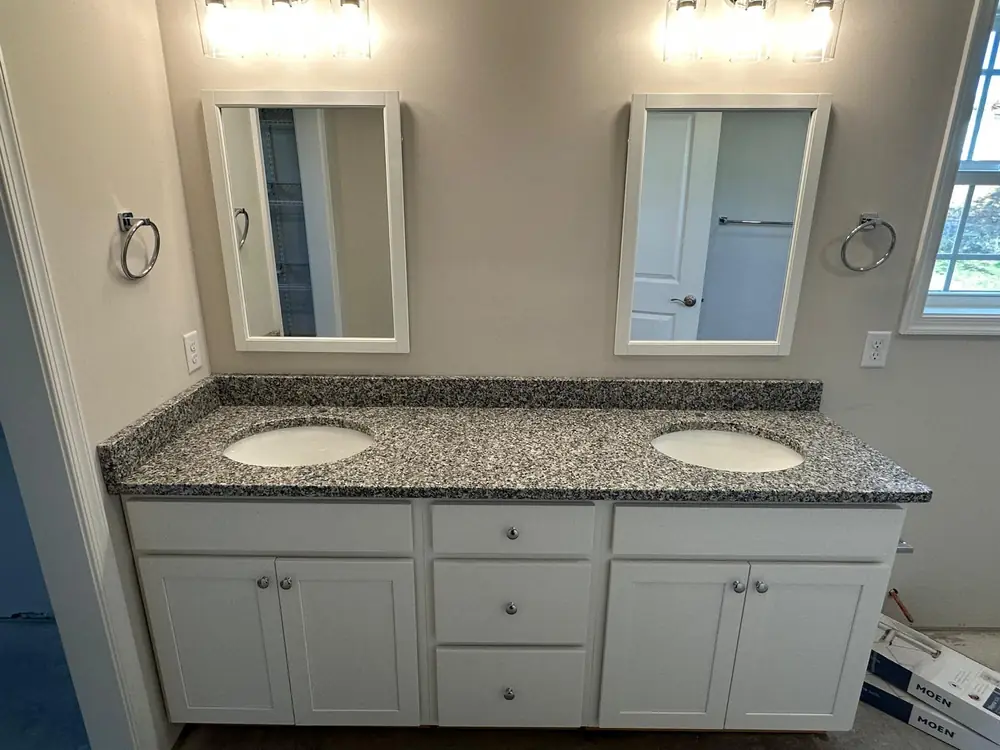 Double vanity with a granite counter and two framed mirrors