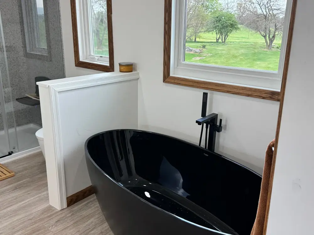 Black freestanding tub with a floor-mounted faucet below a window