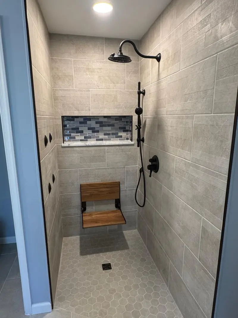 Tiled shower with a folding teak bench and a blue mosaic niche