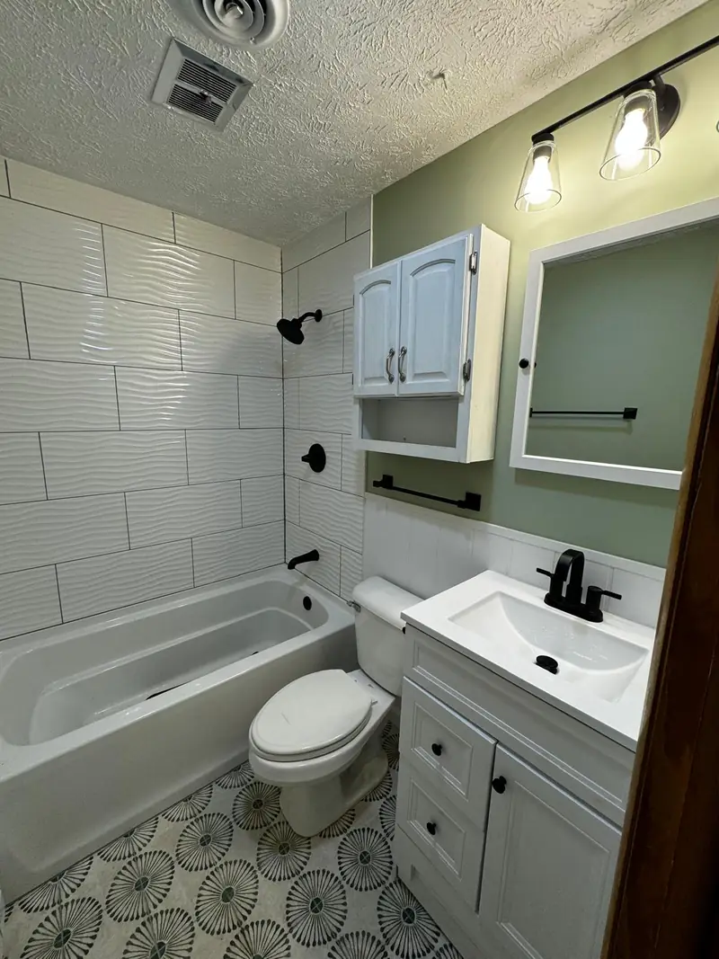 Bathroom with a white tub, wainscoting and a patterned tile floor