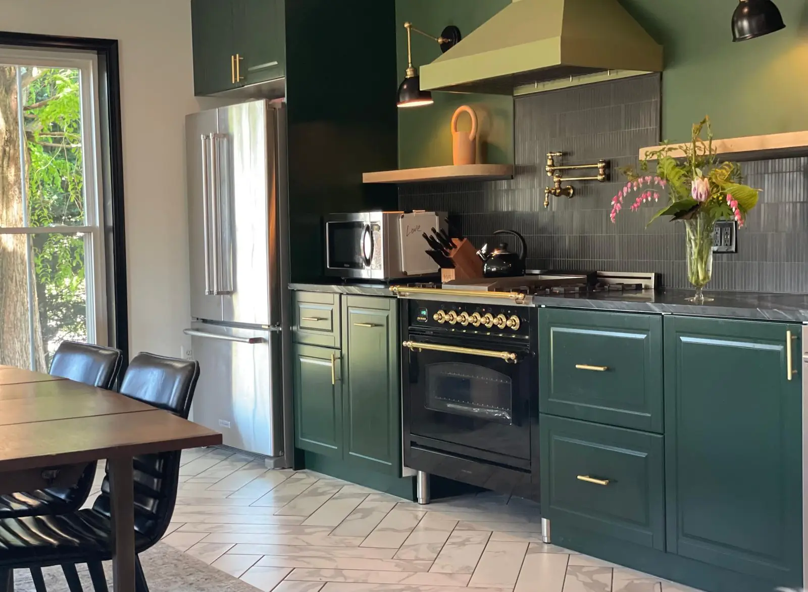 Kitchen with green cabinets, a black range and a herringbone tile floor