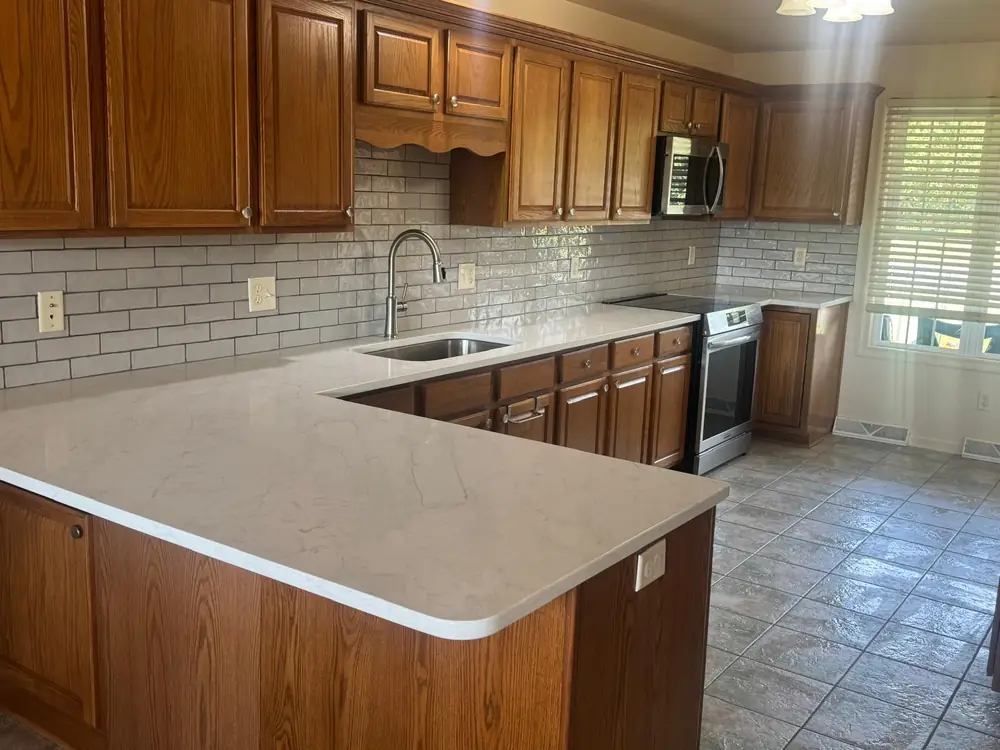 Oak kitchen with new white quartz counters and a subway tile backsplash
