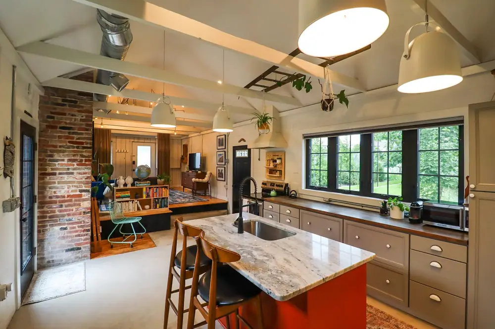 Open kitchen with a red island next to an exposed brick wall