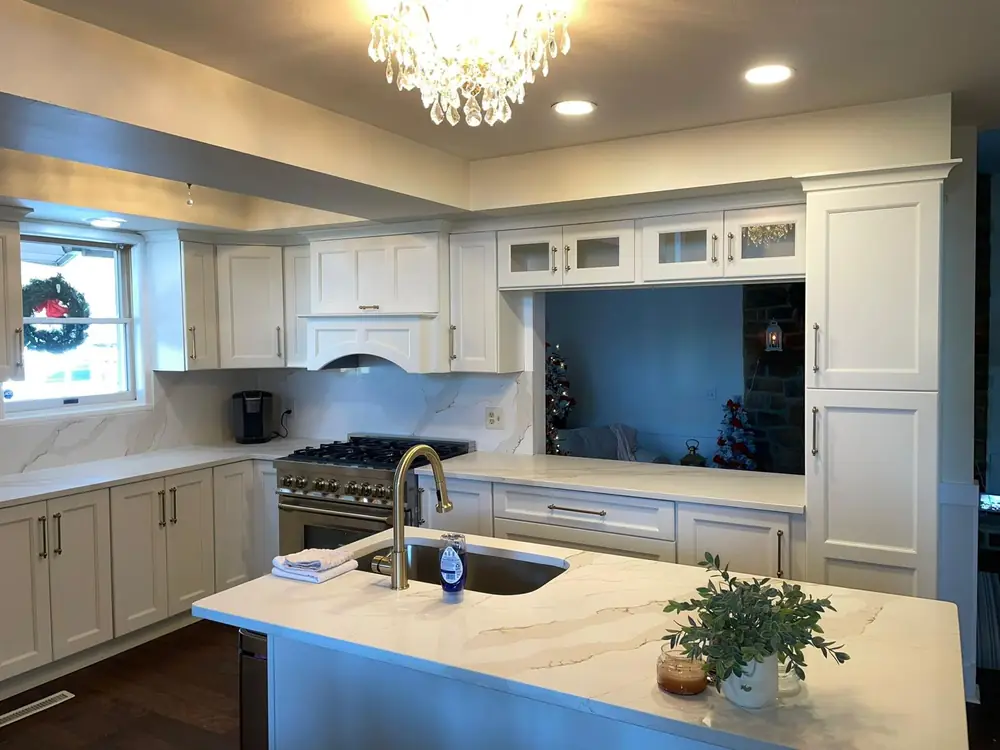 White kitchen with a quartz island and a crystal chandelier